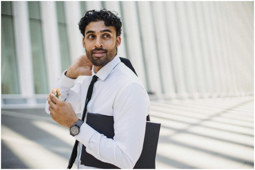 Businessman in formal attire eating a sandwich out