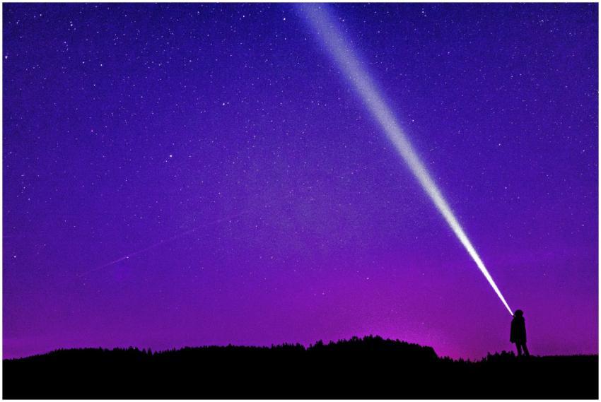 Silhouette of a person shining a flashlight under