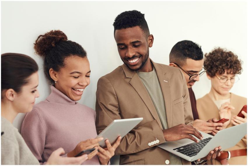 A diverse group of adults happily using technology