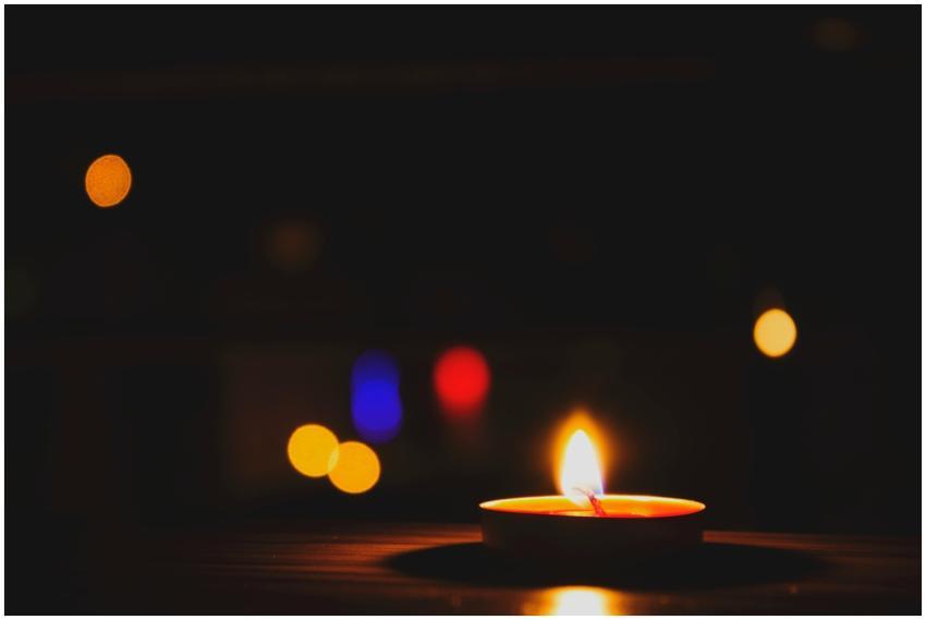 A candle glows warmly in the foreground against a