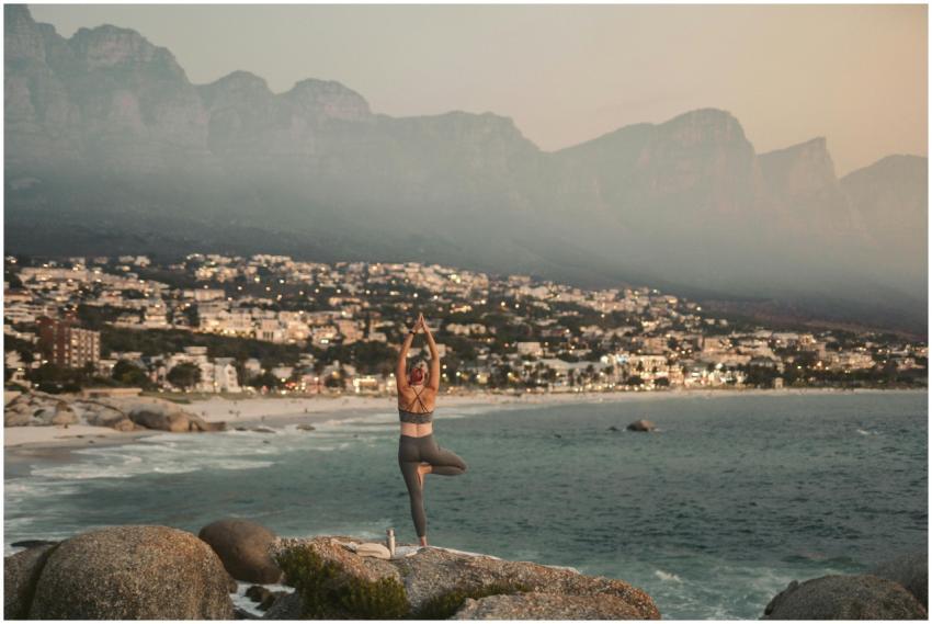A person practices yoga on the rocks overlooking t