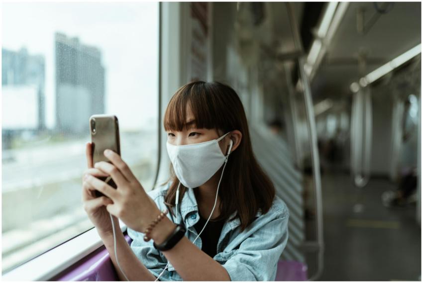 A young woman wearing a face mask on a subway trai