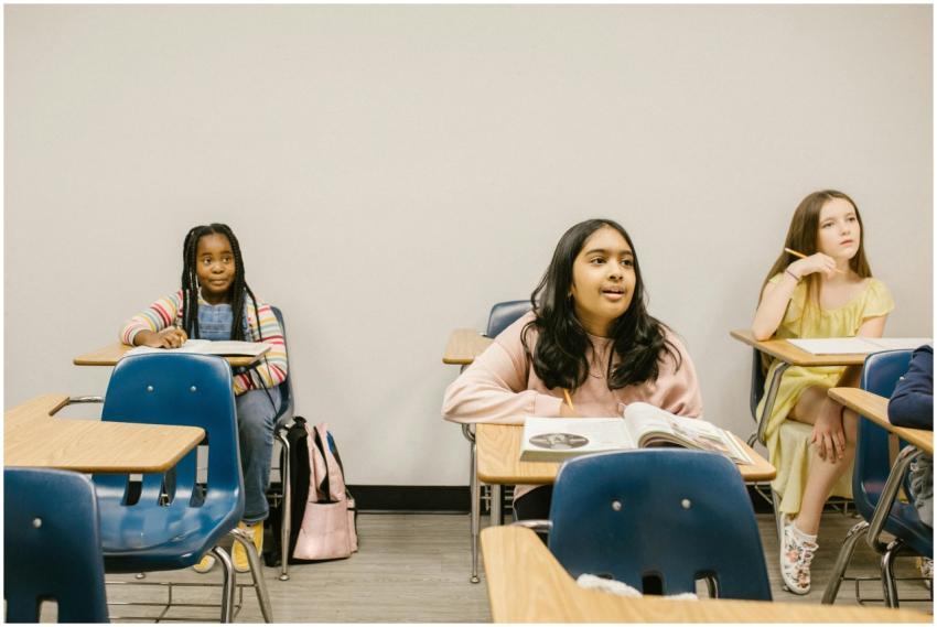 Three diverse students sitting in a classroom, eng
