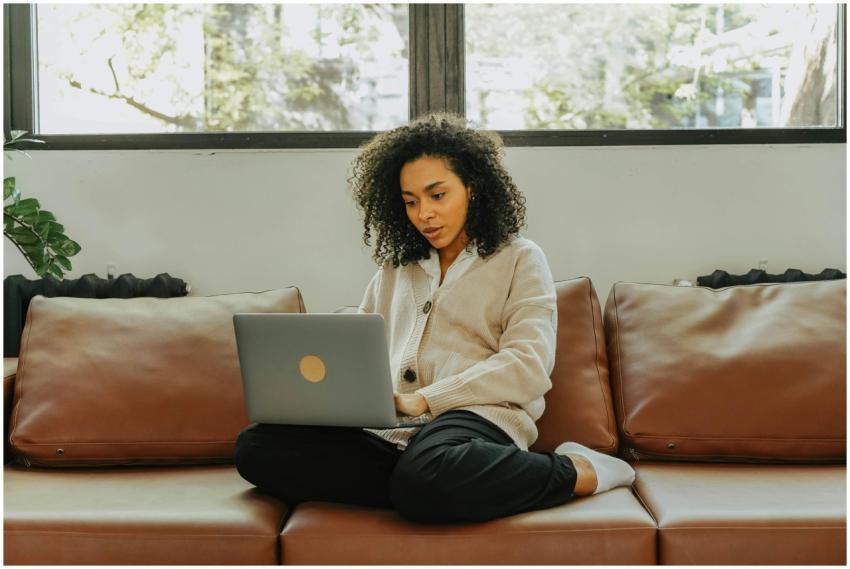 A woman with curly hair sits comfortably on a sofa