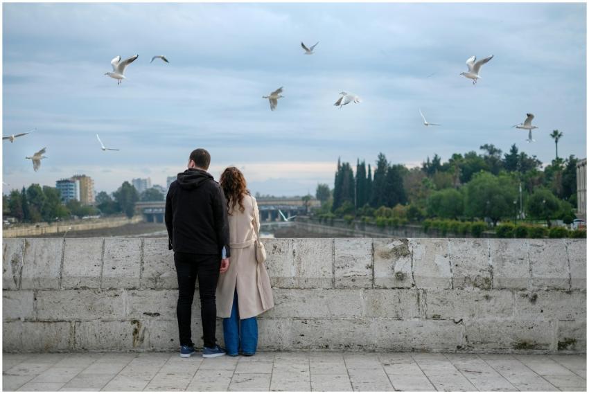 A couple stands on a bridge, observing the urban l