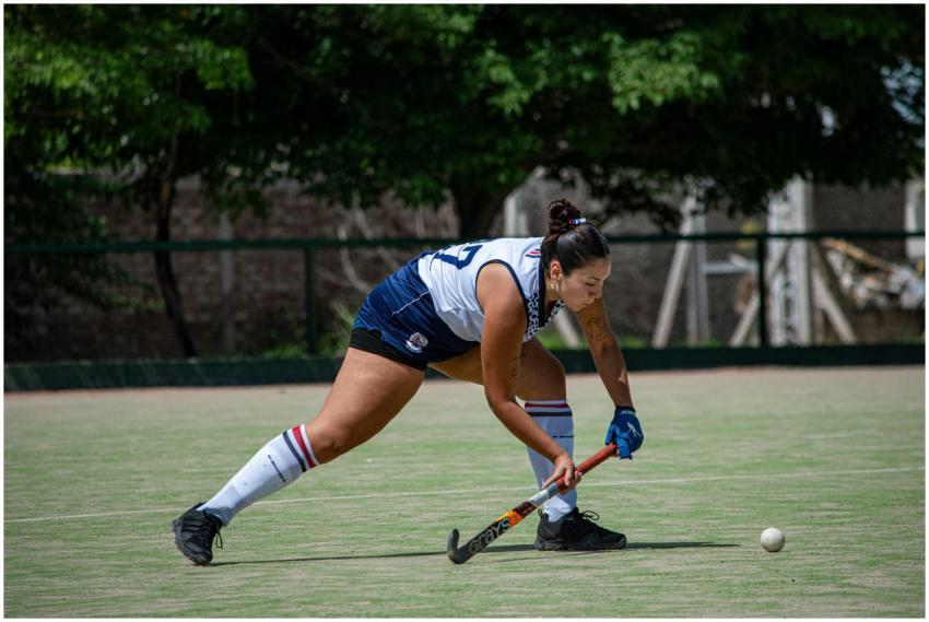 A female field hockey player concentrates as she p