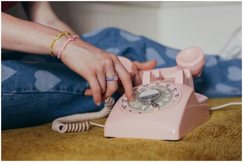 Close-up of a person dialing on a pink rotary phon
