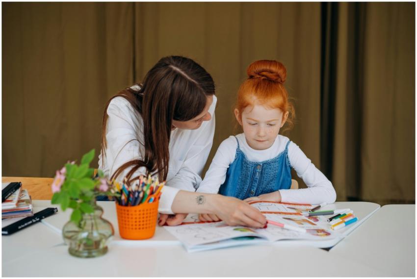 Teacher helps young girl with learning activity in