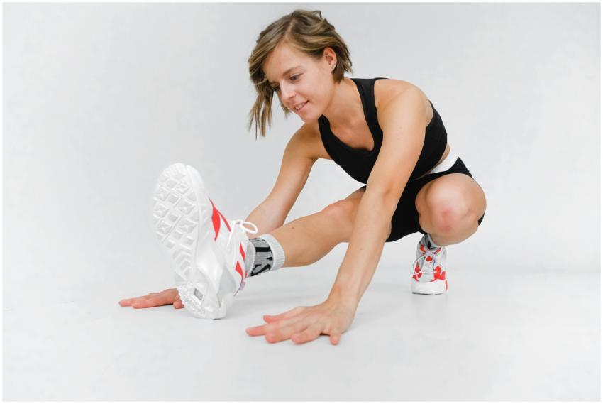 Woman in athletic wear stretching indoors, focused