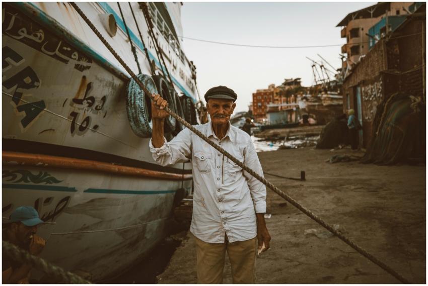 Portrait of an elderly fisherman standing beside a