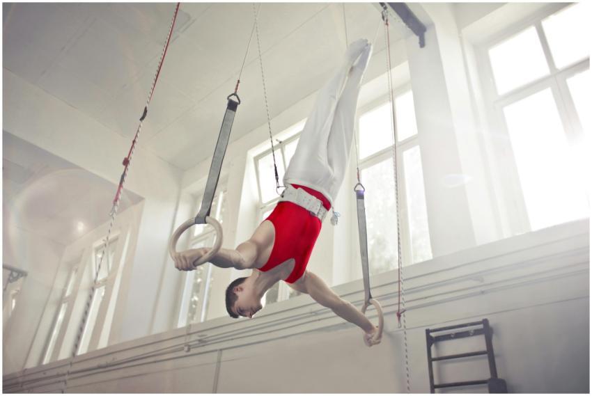 A male gymnast exercises on rings in an indoor gym