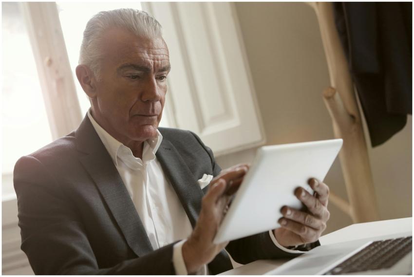 Elderly businessman focused on using a tablet for