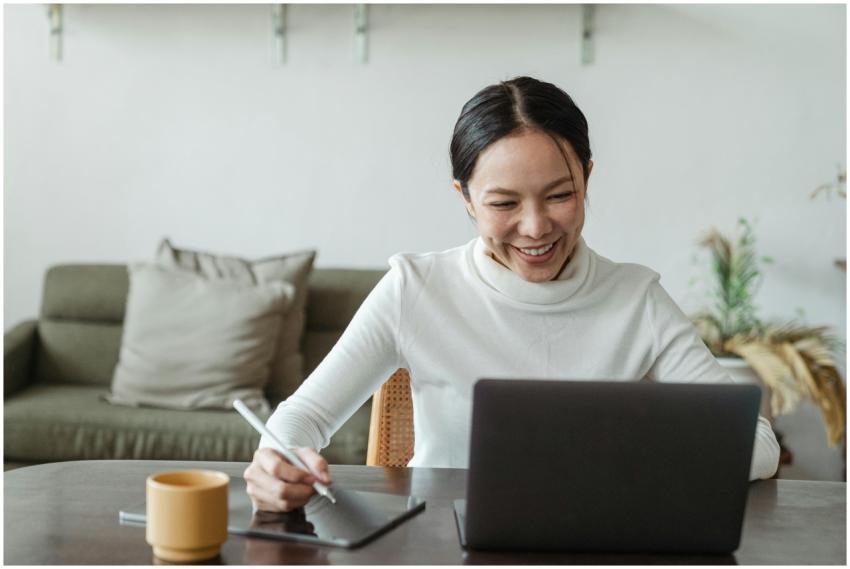 A cheerful woman uses a laptop and tablet for a vi