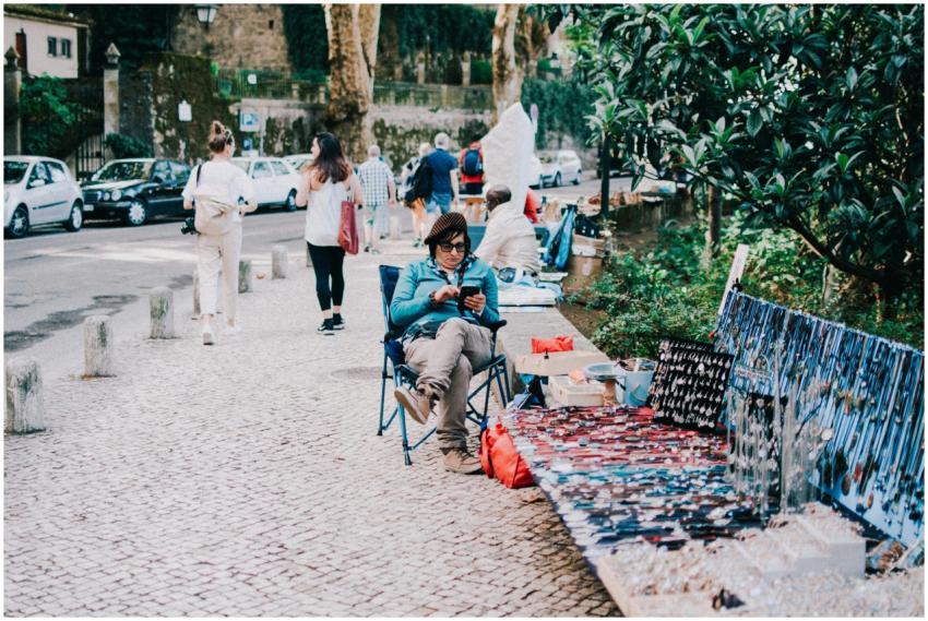 A woman selling handmade jewelry on a sidewalk in