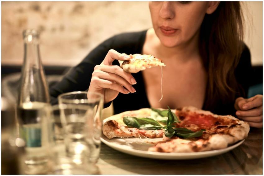 A woman savoring a delicious pizza slice in a cozy