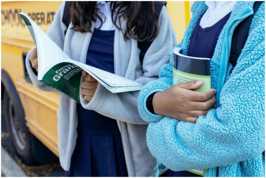 Crop faceless ethnic children holding textbooks wh