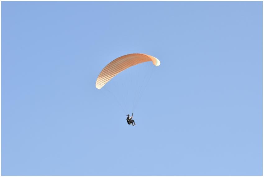A person enjoying paragliding in the clear blue sk