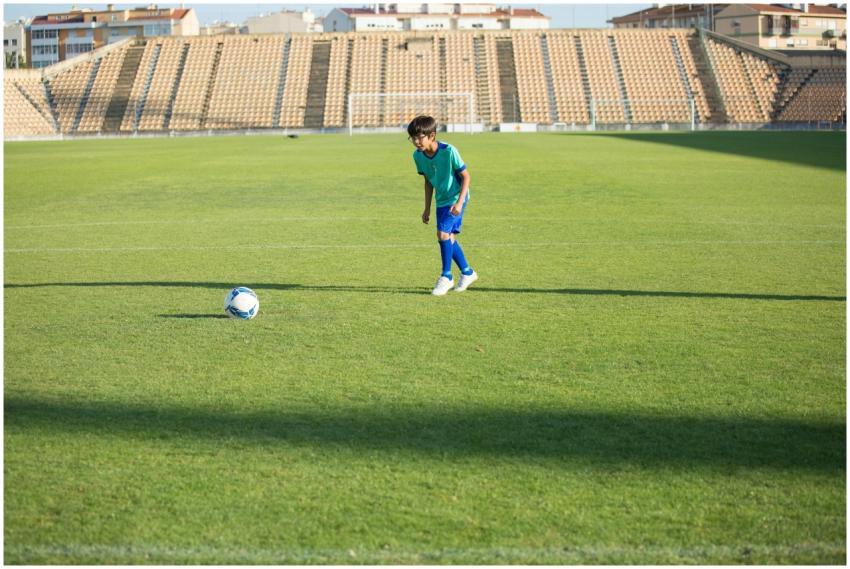 A boy trains on an outdoor soccer field in a stadi