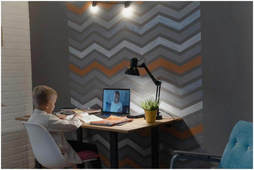 Young boy attending an online class at home with b