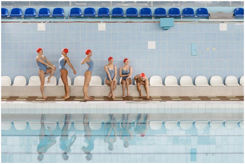 Group of women in swimsuits and caps preparing for