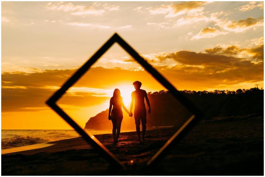 Silhouette of a couple holding hands on a beach du