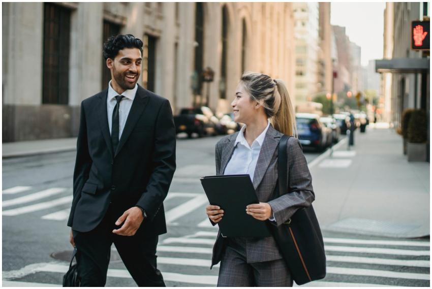 A man and woman in business attire walking across