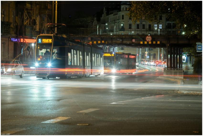 Tram moving at night with light trails in a bustli