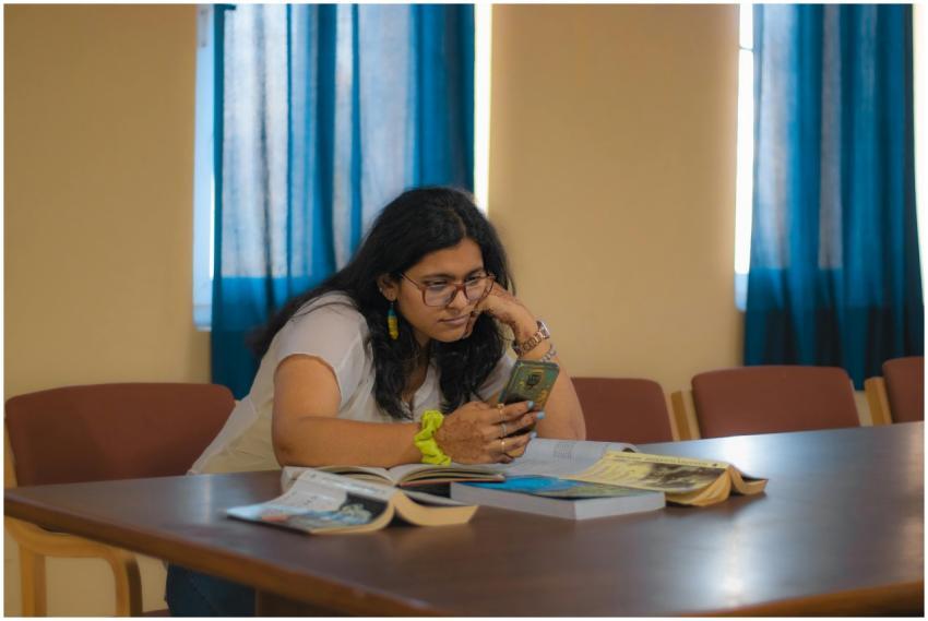 Woman in Delhi library studying with books and sma
