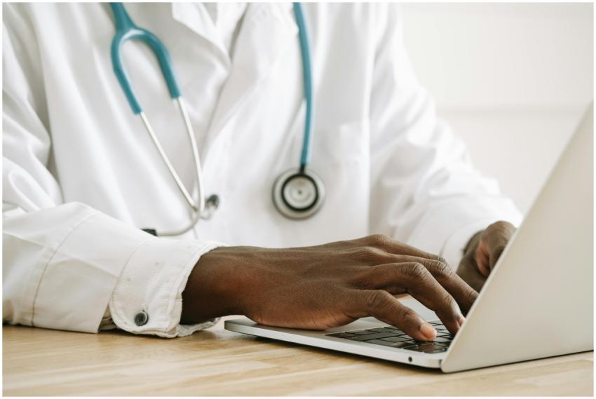 Close-up of a doctor using a laptop, wearing a ste