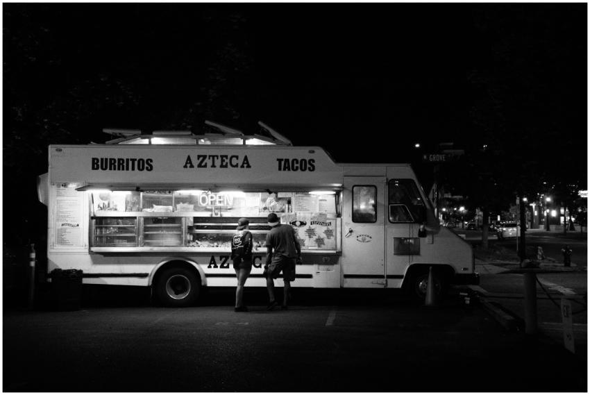 Black and white photo of people buying from a taco