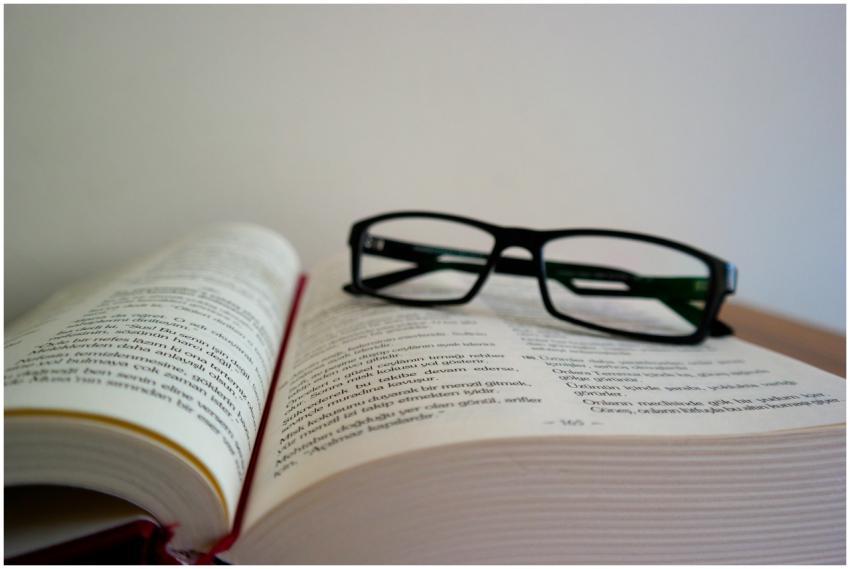 An open book with eyeglasses resting on top, symbo
