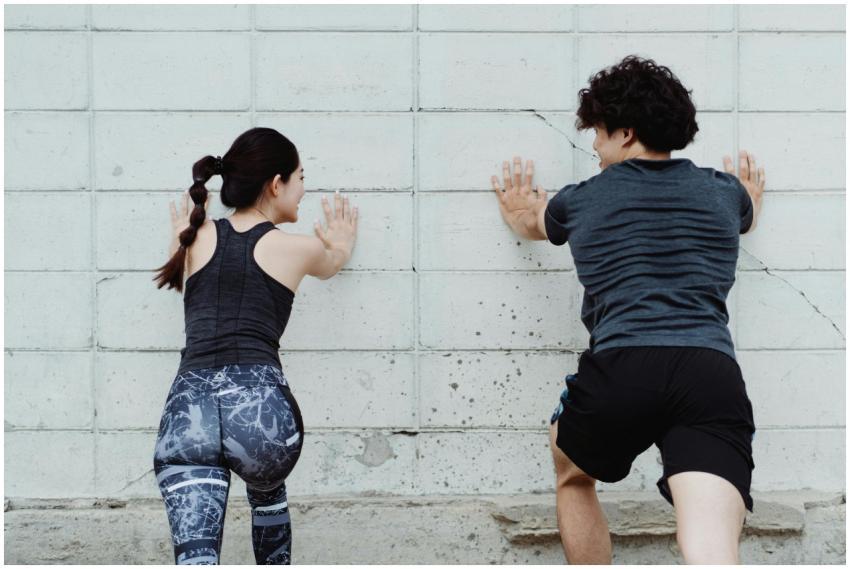 A man and woman push against a wall during an outd