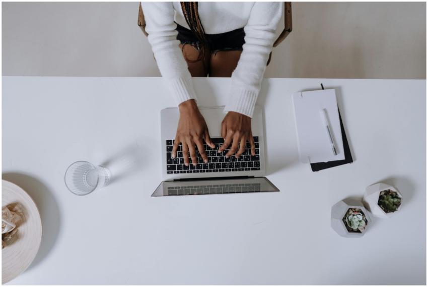 Top view of a woman typing on a laptop at a modern