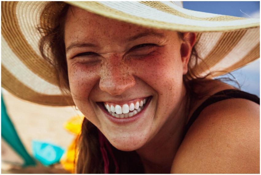 Close-up of a smiling woman with freckles wearing