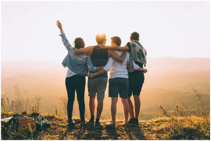 A group of friends embrace while enjoying a sunset