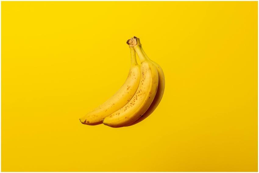 A bunch of ripe yellow bananas against a vivid yel