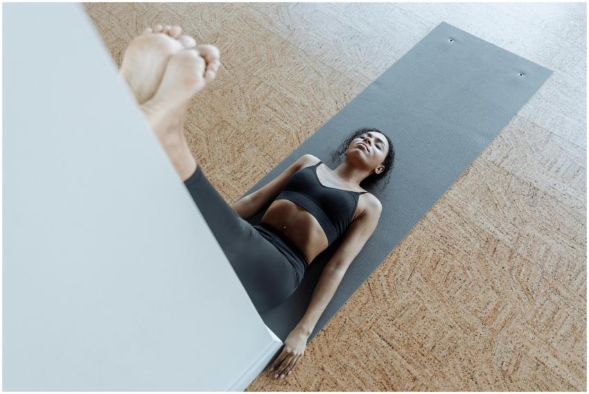 Woman lying on a yoga mat indoors, focusing on rel