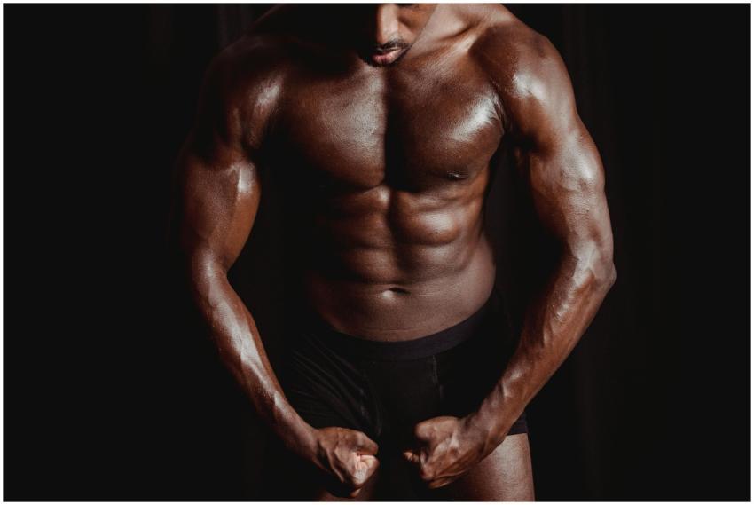 Athletic male bodybuilder flexing muscles in a dra