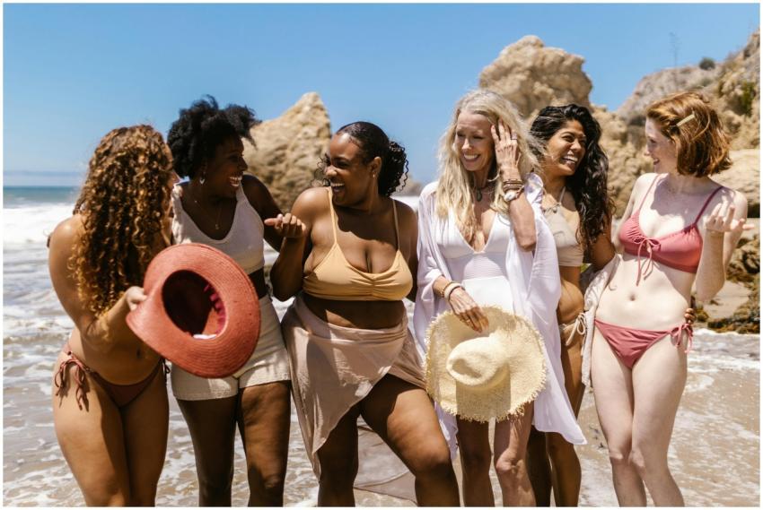 Six diverse women in bathing suits laughing and en
