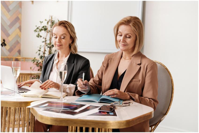 Two mature women in an office setting writing with