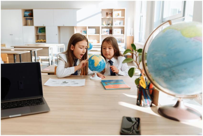 Two young girls explore a globe in a bright classr
