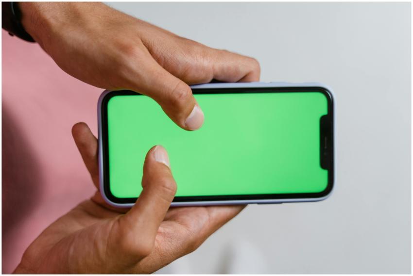 Hands holding smartphone with a green screen, suit