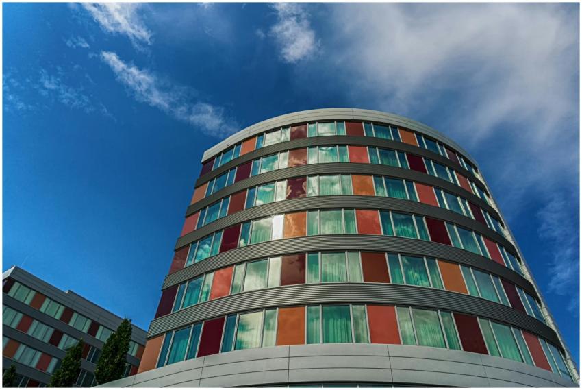 A modern curved building with colorful panels agai