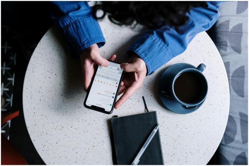 Person using smartphone at table with notebook and