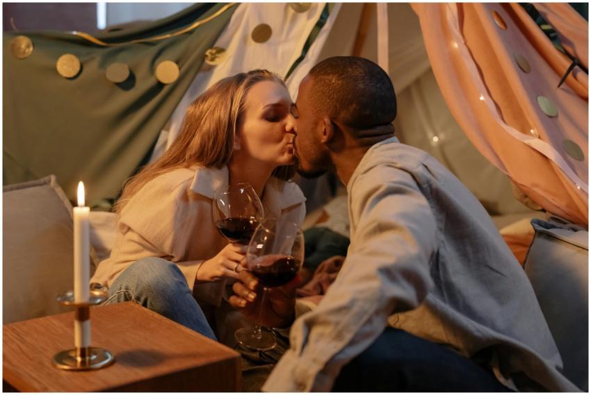 A couple shares a romantic kiss while holding wine