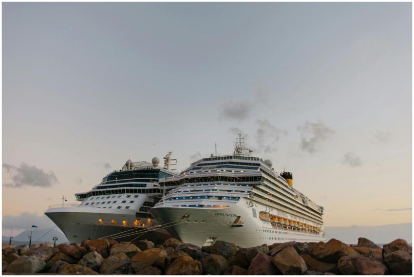 Two large cruise ships moored at sunset near a roc