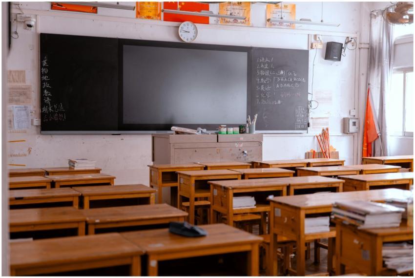 An empty classroom with wooden desks and a blackbo