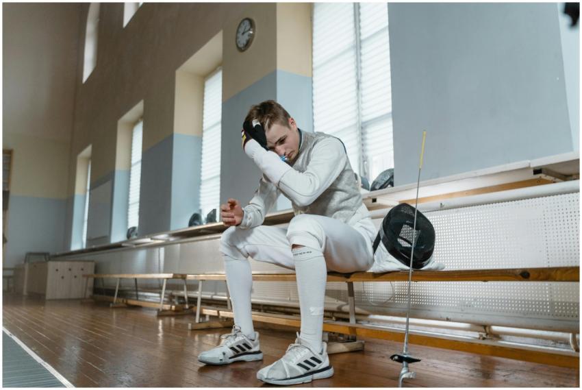 Young male fencer taking a break in a training sal