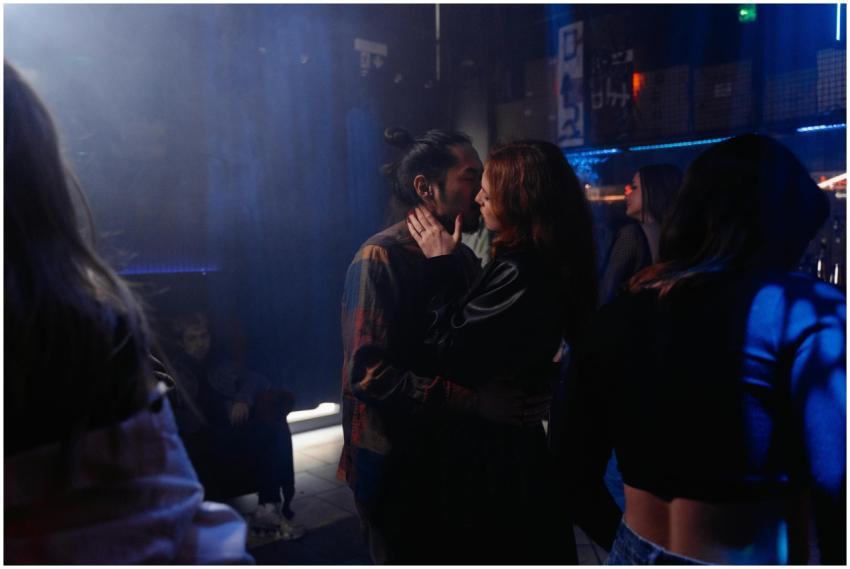 A romantic couple kissing in a lively nightclub wi