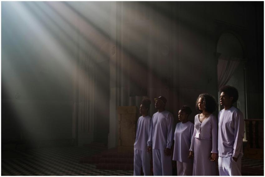 A choir of adults singing under sunbeams in a cath